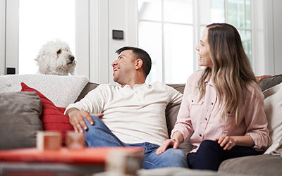Couple sitting on their couch looking at their dog